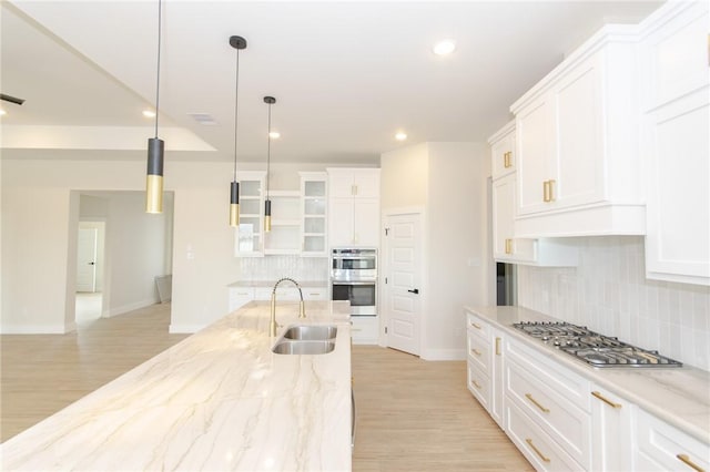 kitchen featuring sink, appliances with stainless steel finishes, pendant lighting, light stone countertops, and white cabinets