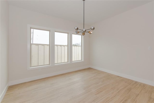 unfurnished room featuring a chandelier and light hardwood / wood-style floors