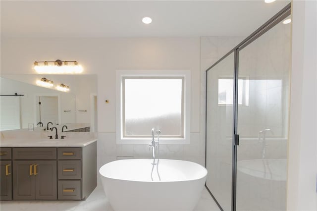 bathroom featuring independent shower and bath, vanity, and tile walls