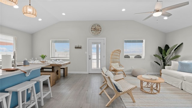 living room with light wood-type flooring, ceiling fan, and vaulted ceiling