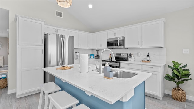 kitchen featuring white cabinets, appliances with stainless steel finishes, and vaulted ceiling