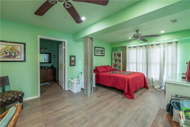 bedroom featuring visible vents, connected bathroom, baseboards, and wood finished floors