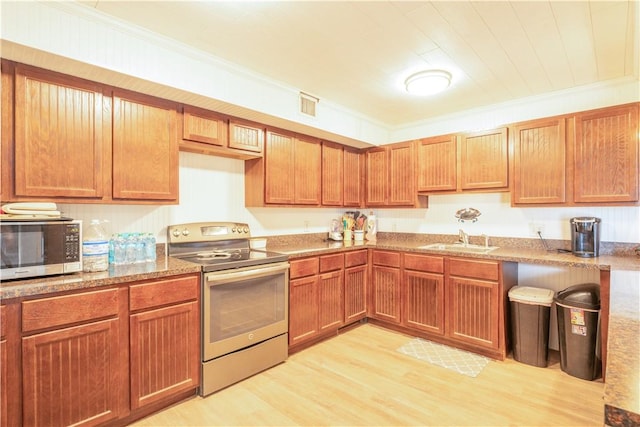 kitchen with appliances with stainless steel finishes, crown molding, a sink, and visible vents