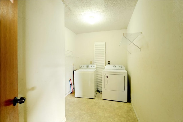 clothes washing area featuring laundry area, a textured ceiling, baseboards, and washer and dryer