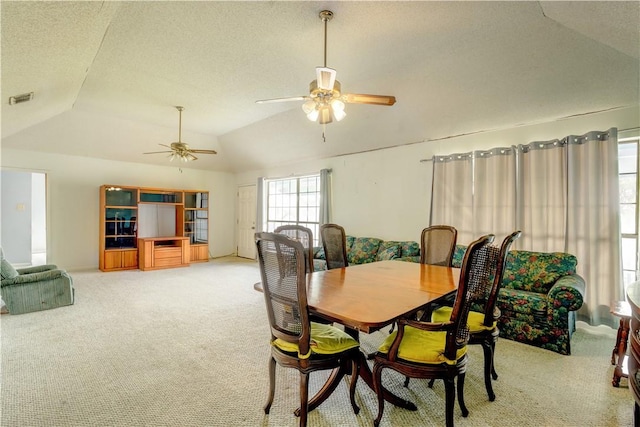 dining area featuring lofted ceiling, visible vents, light carpet, ceiling fan, and a textured ceiling