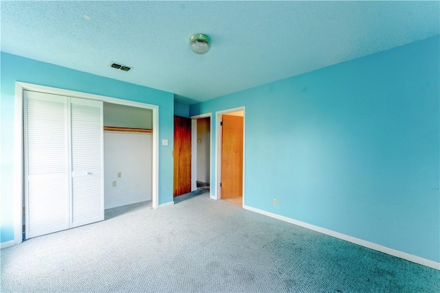 unfurnished bedroom with baseboards, visible vents, a textured ceiling, carpet flooring, and a closet