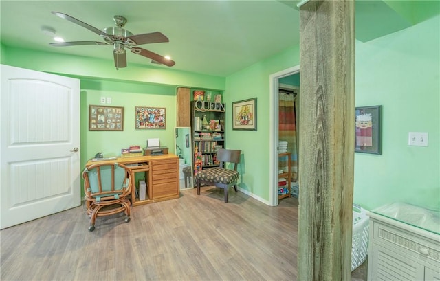 office space featuring a ceiling fan, baseboards, and wood finished floors