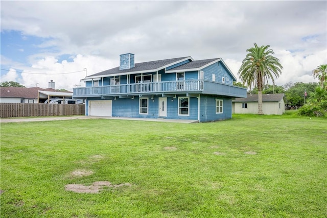 rear view of house with a lawn, an attached garage, and fence