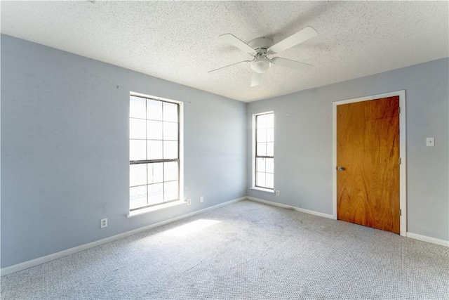 carpeted spare room featuring a ceiling fan, baseboards, and a textured ceiling