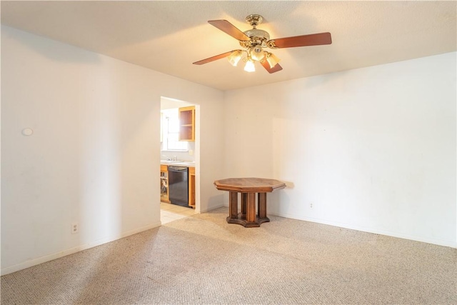 unfurnished room with ceiling fan, baseboards, a sink, and light colored carpet