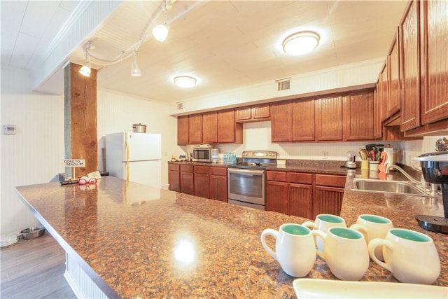 kitchen featuring dark countertops, a peninsula, appliances with stainless steel finishes, and a sink