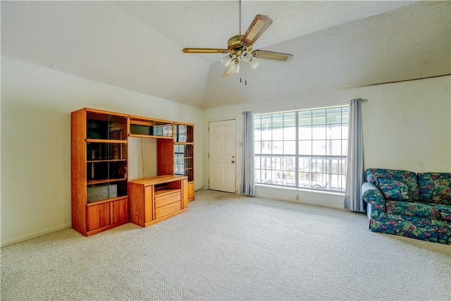 living area featuring ceiling fan, vaulted ceiling, a textured ceiling, and light colored carpet