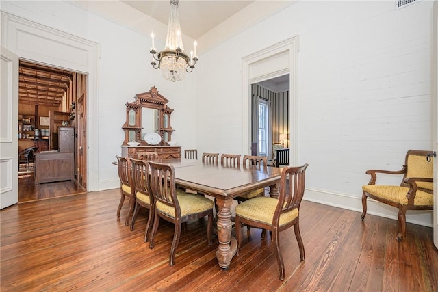 dining area featuring dark wood-type flooring and a chandelier