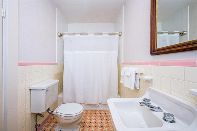 full bathroom featuring shower / bath combination with curtain, sink, tile patterned flooring, toilet, and tile walls