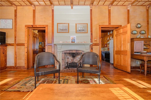 sitting room featuring a brick fireplace, wood walls, wood ceiling, and wood-type flooring