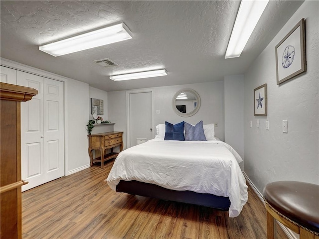 bedroom with wood-type flooring and a textured ceiling