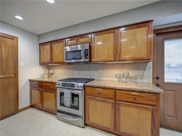 kitchen with light stone countertops, appliances with stainless steel finishes, and decorative backsplash