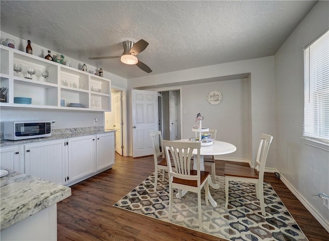 dining space with dark wood-type flooring, ceiling fan, and a textured ceiling