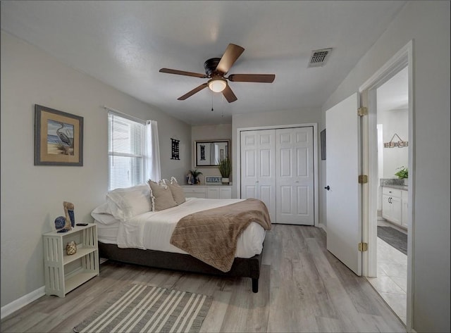 bedroom with ceiling fan, ensuite bathroom, light wood-type flooring, and a closet