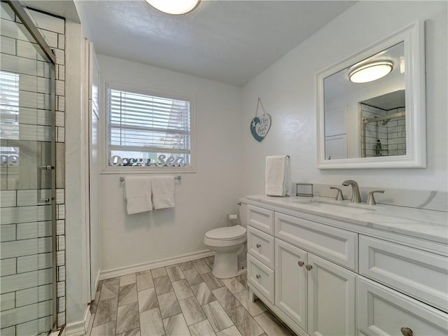 bathroom featuring a shower with door, vanity, and toilet