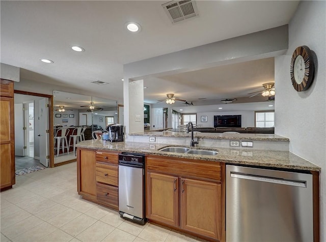 kitchen featuring sink, stainless steel dishwasher, kitchen peninsula, a healthy amount of sunlight, and light stone countertops