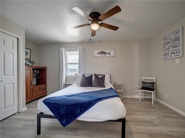 bedroom with ceiling fan, light hardwood / wood-style flooring, and a textured ceiling