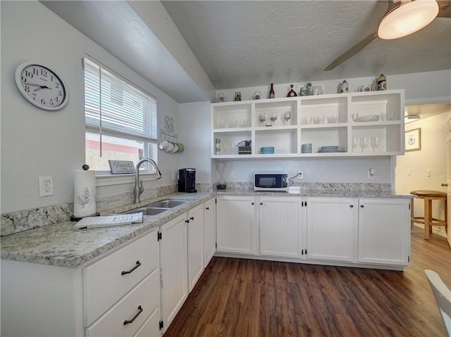 kitchen featuring light stone counters, dark wood-type flooring, sink, and white cabinets