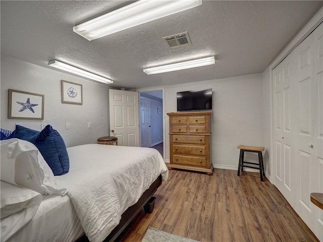 bedroom with wood-type flooring, a textured ceiling, and a closet