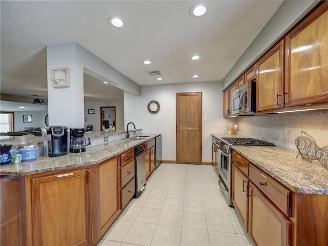 kitchen featuring sink, light tile patterned floors, stainless steel appliances, light stone counters, and kitchen peninsula