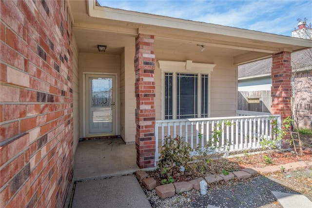 entrance to property with covered porch and brick siding