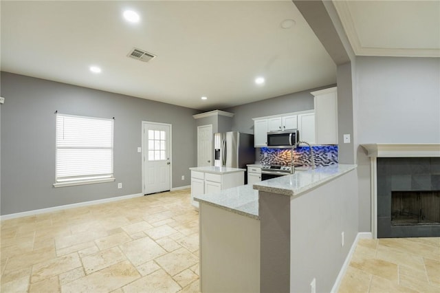 kitchen featuring white cabinetry, light stone countertops, kitchen peninsula, and appliances with stainless steel finishes