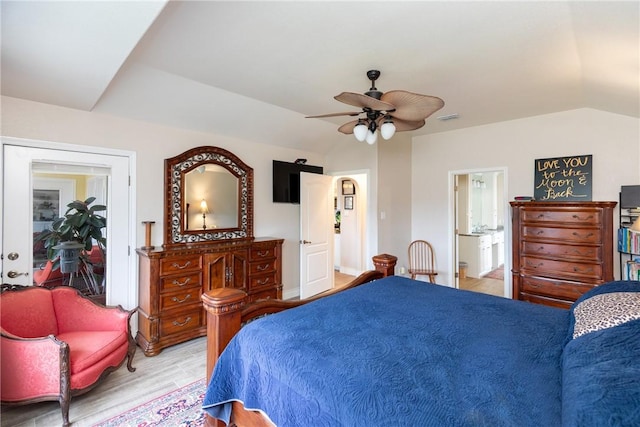 bedroom featuring ceiling fan, light wood-type flooring, ensuite bath, and vaulted ceiling