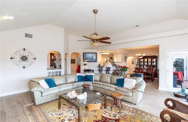 living room with ceiling fan with notable chandelier, light hardwood / wood-style floors, and lofted ceiling