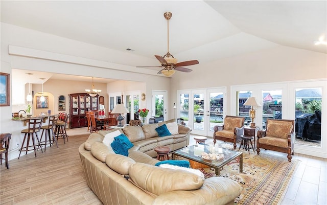 living room with ceiling fan with notable chandelier, light hardwood / wood-style flooring, lofted ceiling, and french doors