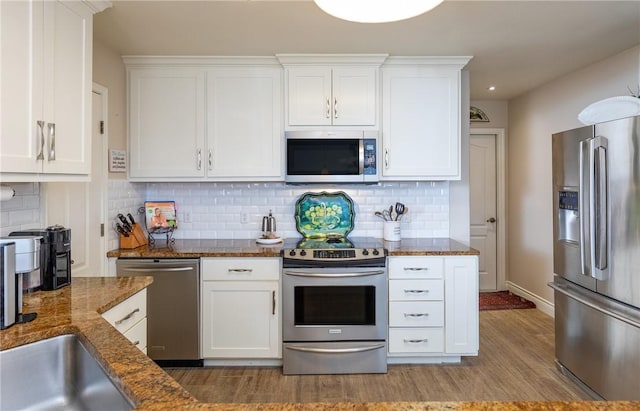 kitchen featuring tasteful backsplash, stainless steel appliances, white cabinets, and dark stone counters