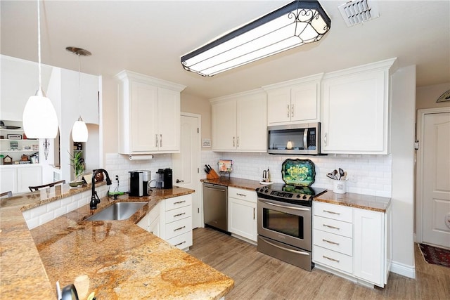 kitchen featuring hanging light fixtures, white cabinets, sink, and stainless steel appliances