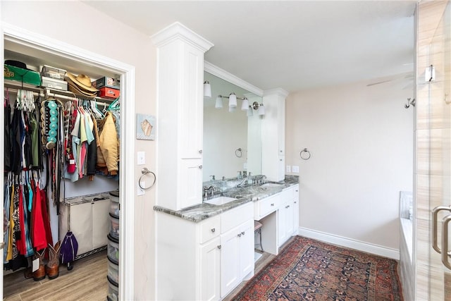 bathroom featuring wood-type flooring, a bathtub, vanity, and ornamental molding