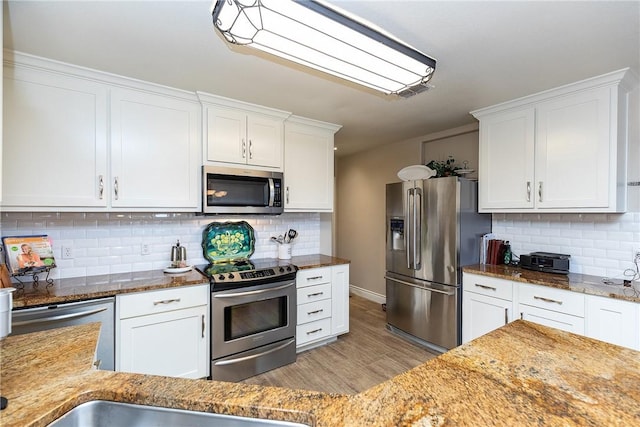 kitchen featuring appliances with stainless steel finishes, white cabinetry, and tasteful backsplash