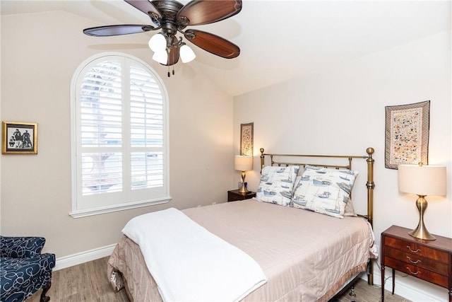 bedroom with vaulted ceiling, ceiling fan, hardwood / wood-style flooring, and multiple windows