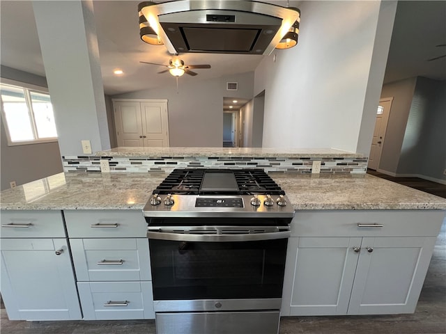 kitchen featuring backsplash, stainless steel gas stove, white cabinets, and lofted ceiling