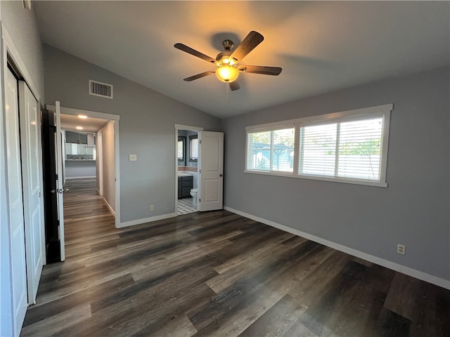 unfurnished bedroom featuring ensuite bathroom, dark hardwood / wood-style flooring, ceiling fan, and vaulted ceiling