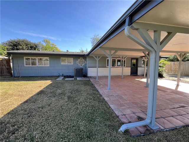 rear view of property with a lawn, a patio, and central AC