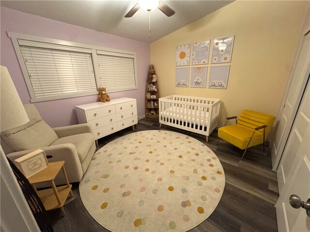 bedroom with vaulted ceiling, ceiling fan, a nursery area, dark hardwood / wood-style flooring, and a closet