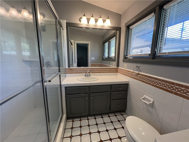 bathroom featuring vanity, toilet, tile walls, and a shower with shower door