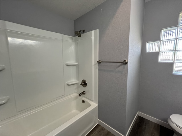 bathroom featuring hardwood / wood-style flooring, toilet, and shower / washtub combination