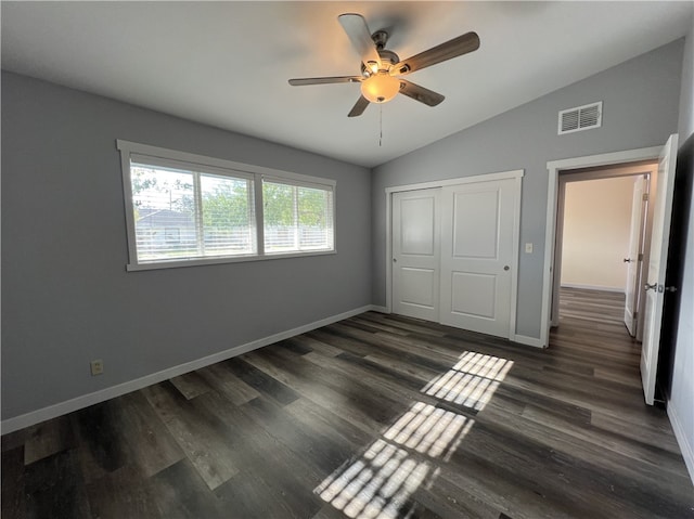 unfurnished bedroom with a closet, vaulted ceiling, ceiling fan, and dark wood-type flooring