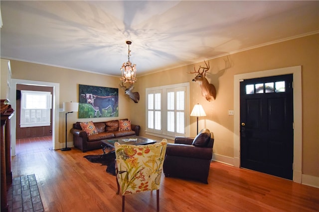 living room with hardwood / wood-style floors, a wealth of natural light, a notable chandelier, and crown molding