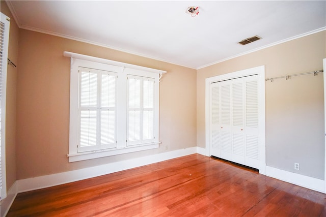 unfurnished bedroom featuring a closet, hardwood / wood-style floors, and ornamental molding