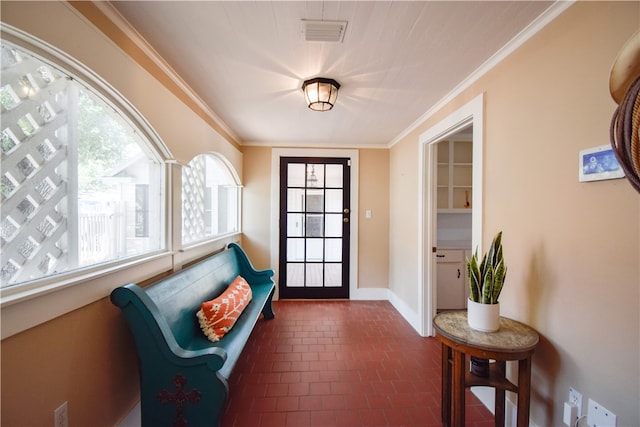 doorway with dark tile patterned floors and ornamental molding