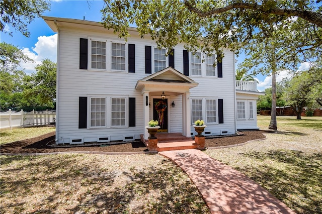 colonial inspired home featuring a front yard and a balcony